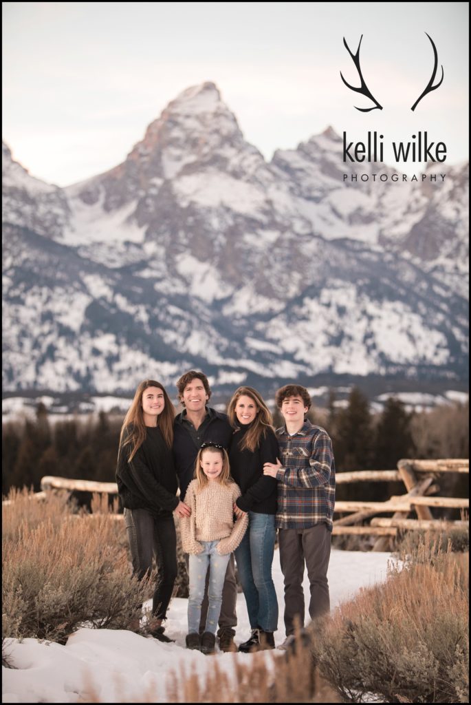 a family in front of the Tetons at sunset in the winter for family portraits