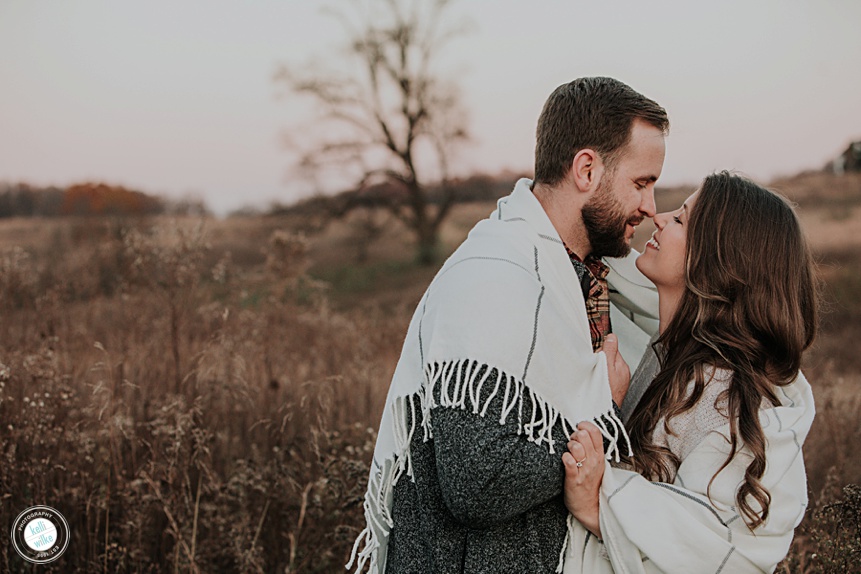 couple wrapped in a blanket outside in a field engagement photos
