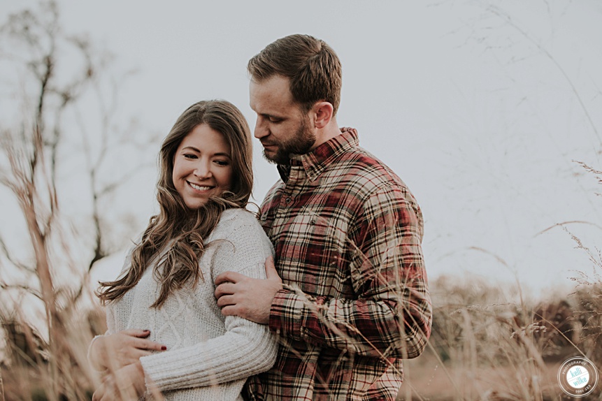 engagement photo in a field in the fall with plaid and cream clothing
