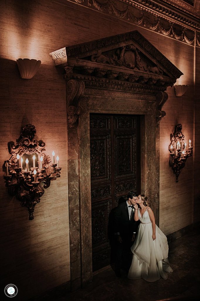 portrait of bride and groom standing in front of the great hall doors at the hotel dupont in wilmington delaware