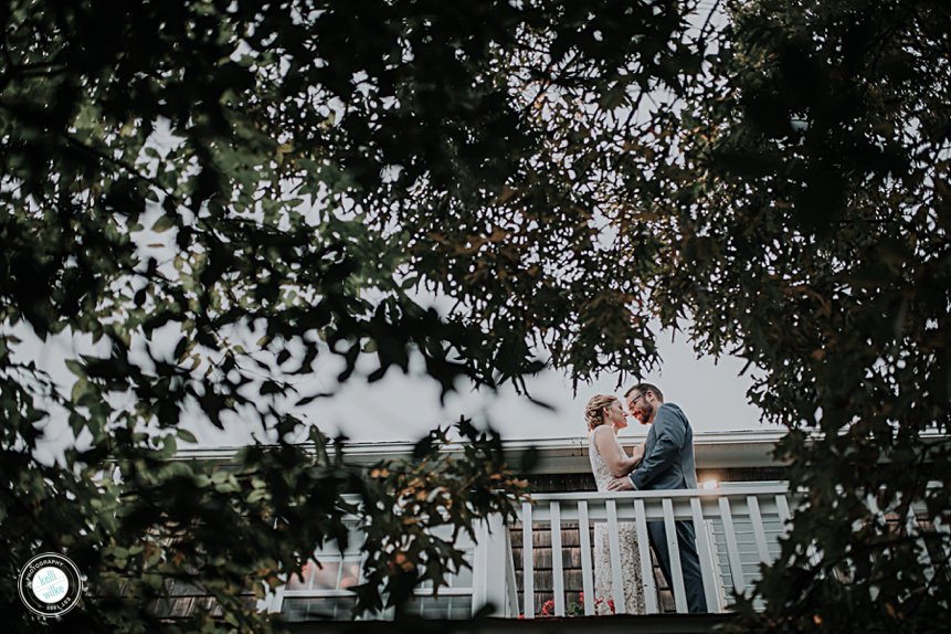 bride and groom stand on an upper deck amongst the trees for a portrait on their wedding day