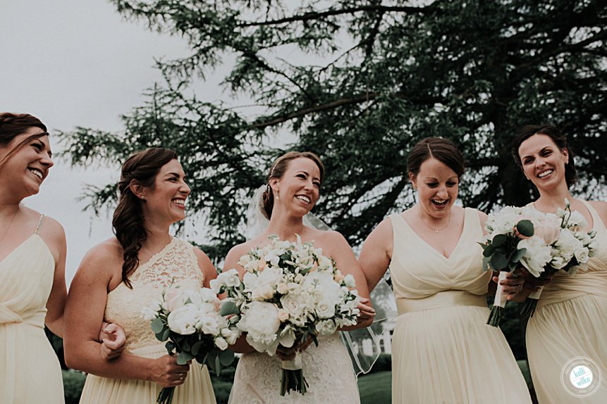 bridesmaids laughing together outside in their yellow dresses and soft yellow and cream flowers by yukie