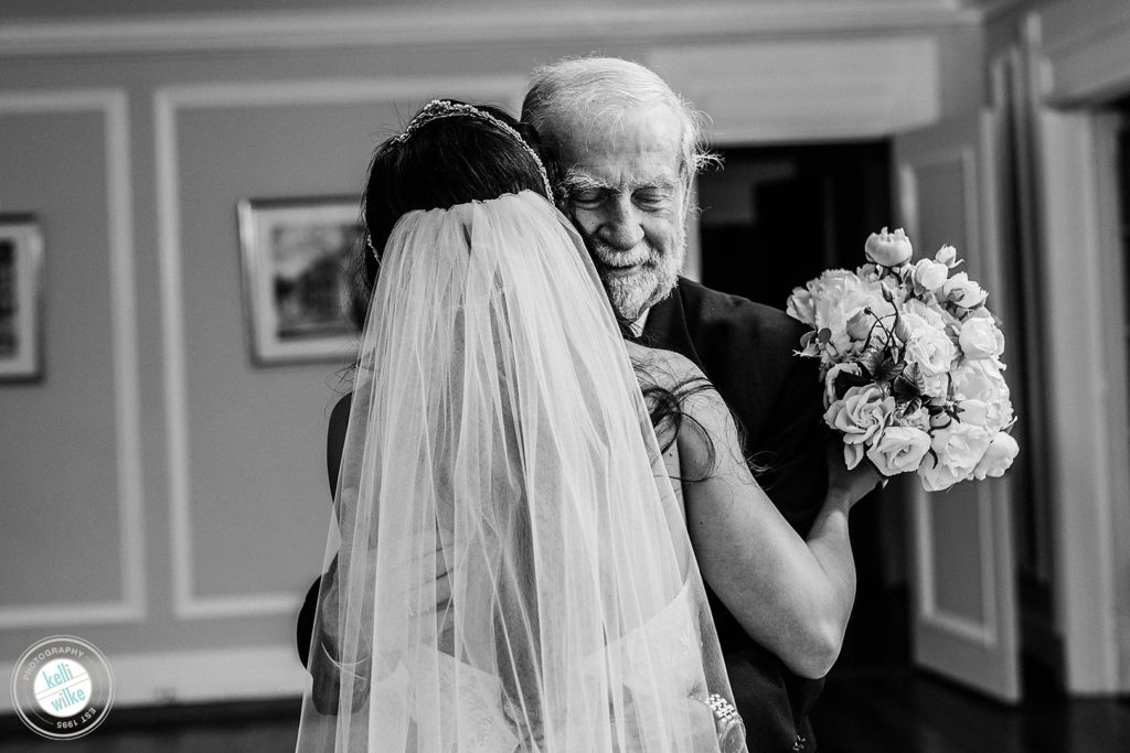 The father of the bride hugs his daughter during a First look or reveal with a bride and her father at Greenville Country Club in Greenville DE
