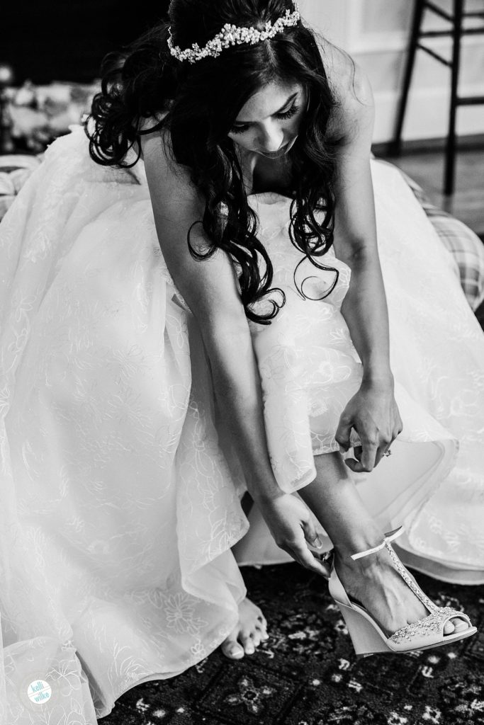 Bride puts on her Badgley Mischka wedding shoes while getting ready for her ceremony