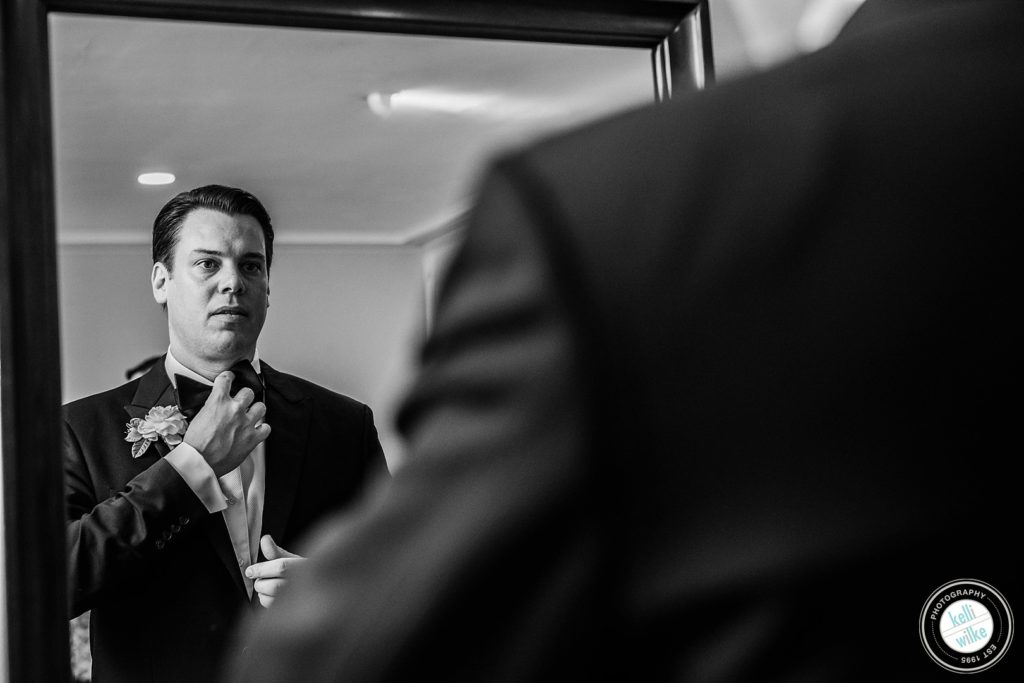groom adjusts his tie before his wedding ceremony at Greenville Country Club in Greenville DE