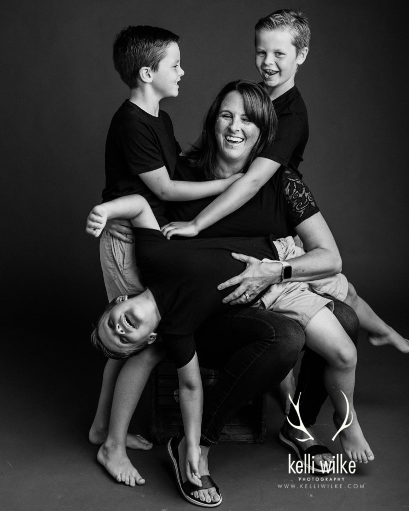 mother joking with her boys in a black and white studio portrait