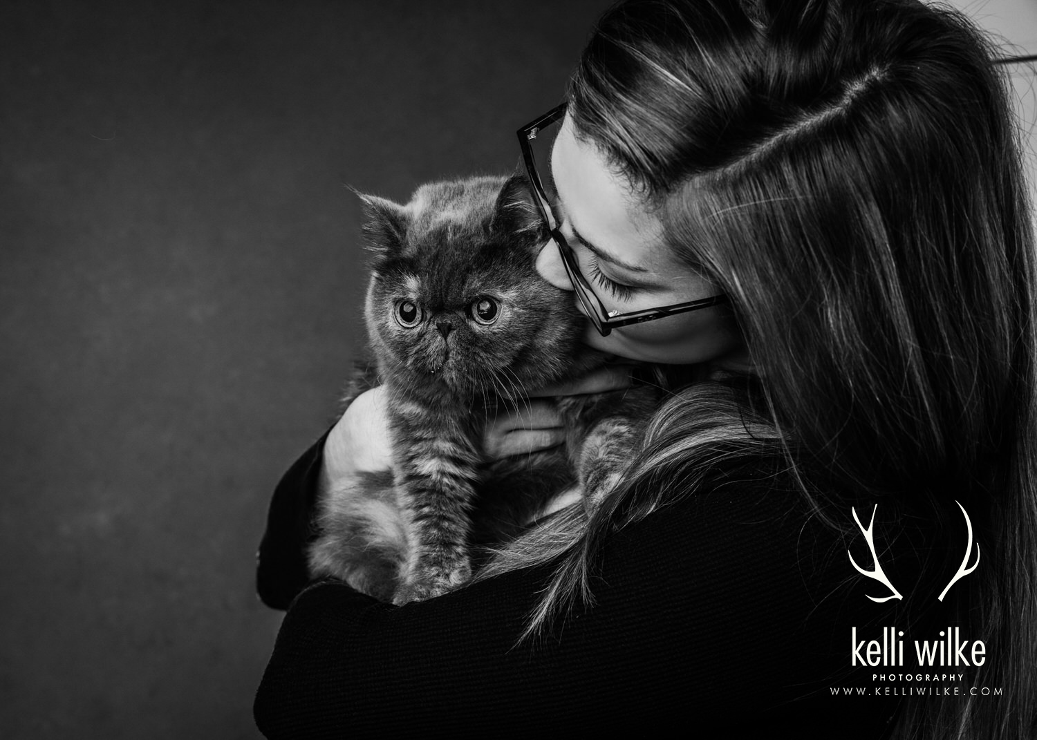 A black and white picture of a woman snuggling a small gray cat during a pet portrait session in Wilmington, Delaware by Kelli Wilke Photography. 
