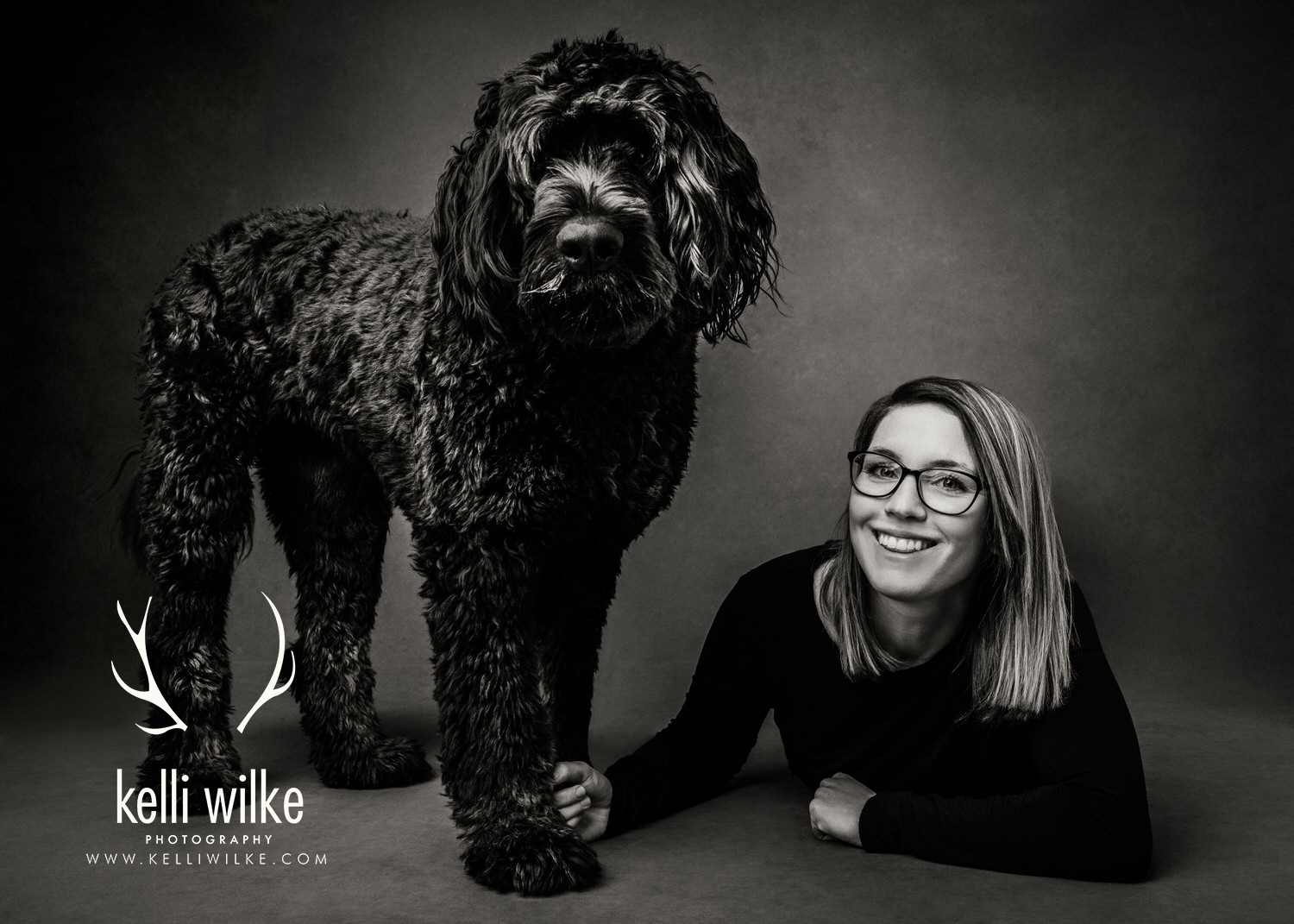 A black and white portrait of a large, shaggy black dog and his owner during a pet portrait session in Wilmington Delaware by Kelli Wilke Photography. 