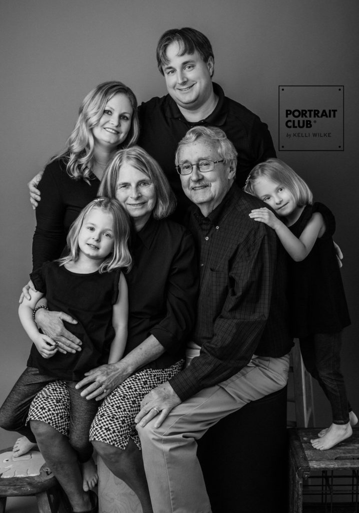 A formal portrait of a family smiling at the camera during a family photo session with Portrait Club by Kelli Wilke. 