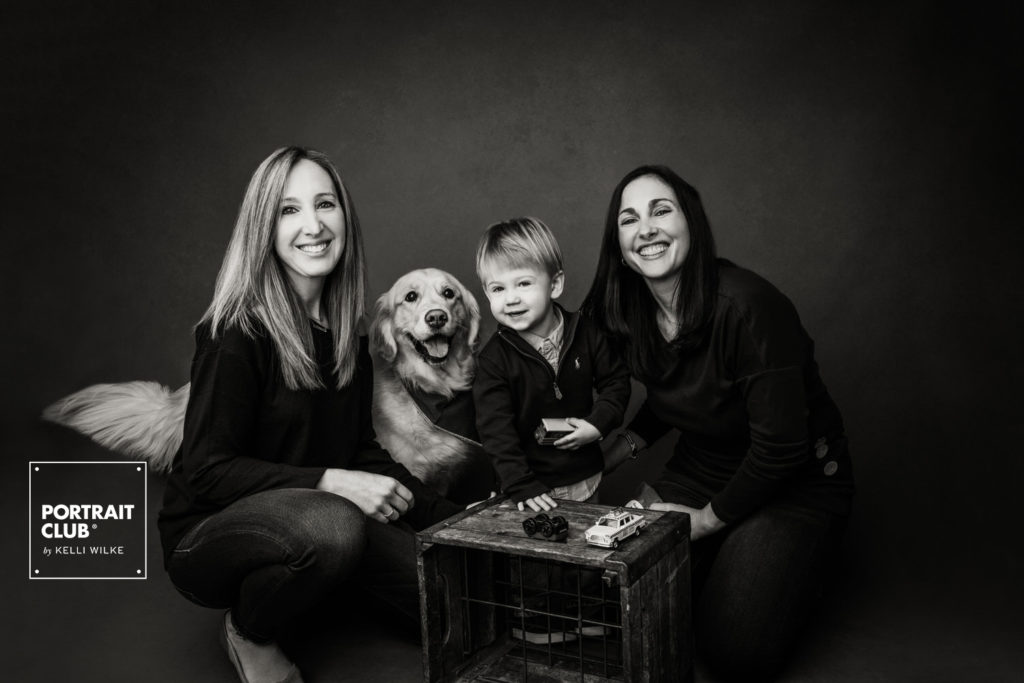 A portrait of a family and their dog smiling at the camera during their family photo session with Portrait Club by Kelli WIlke. 