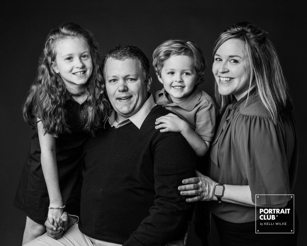 A formal picture of a family with a little boy and girl smiling at the camera during a family photo session with Portrait Club by Kelli Wilke. 
